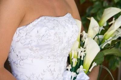 Natasha has a bridal bouquet of white calla lilies and stephanotis and bear grass with a white satin stem wrap.