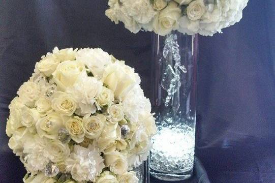 Elegantin white. Cascade bouquet of white roses, spray roses, carnations, fuji mums with coordinating centerpiece on glass cylinder