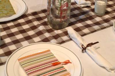 To complete the country theme, we used brown check gingham for table runners and decorated with a mix of antique glass, pitchers, single flower buds, Mexican corn, and candles.