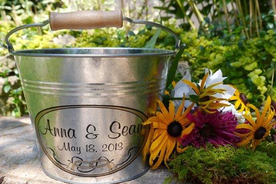 Add a custom touch to your rustic wedding with this personalized metal pail. Made from pristine galvanized steel, it features a solid wood handle and wedding graphics. Fill it with flowers, favors, programs or bird seed bundles.
