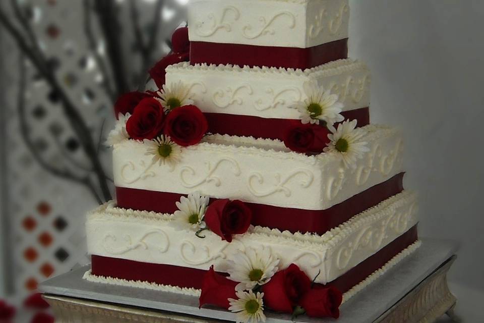 Square wedding cake with red ribbons and roses
