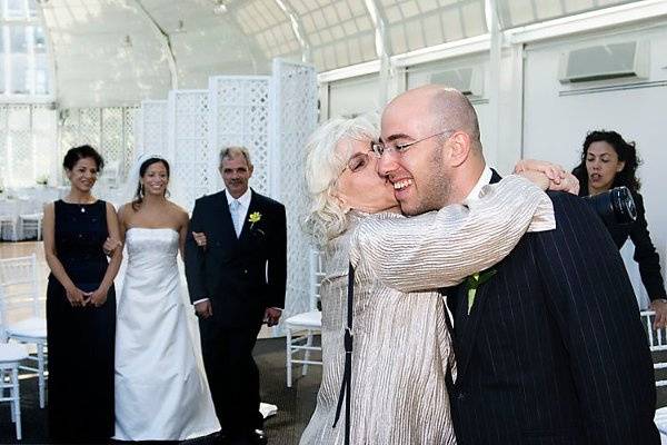 Brooklyn, New York. Jewish wedding. Mother kissing groom in recetion area.