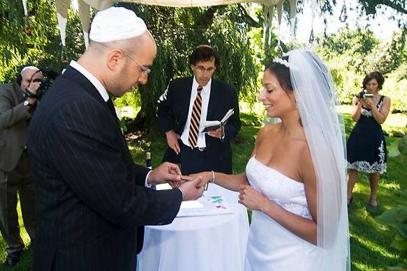 Brooklyn Botanical Ggarden, New York. Jewish wedding. Groom passing ring to bride's finger at altar.