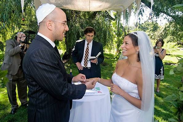 Brooklyn Botanical Ggarden, New York. Jewish wedding. Groom passing ring to bride's finger at altar.