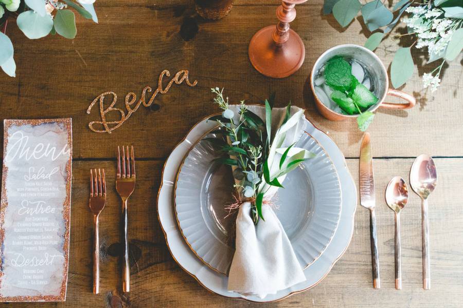 The perfect place setting was created for this Georgia wedding shoot with gray plates, copper silverware, watercolor menus glamed up with copper glitter, custom laser cut glitter place cards, and a napkin tied up with a copper wire ribbon. Copper votive holders and centerpieces set the tone for a romantic reception dinner, with copper prisms adorned with florals from Stylish Stems hanging beautifully above.