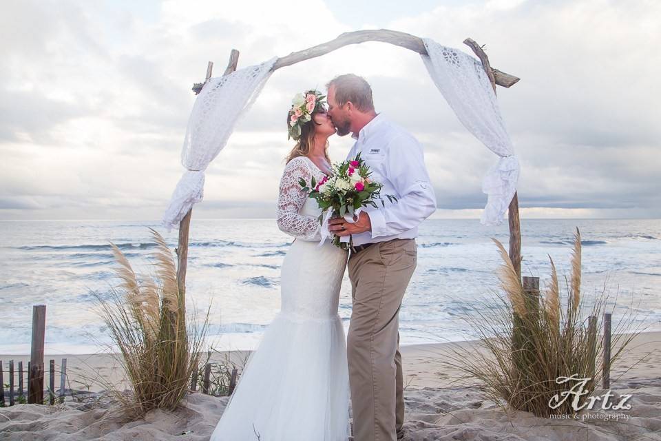 Couple kiss underneath the wedding arch