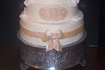 This is a fondant covered cake with fondant ribbons and bows. A sugar monogram plaque adorned with the couples initials pull this look together. The cake is topped off with sugar roses hand tinted to match the cake colors. Sugar rose petals complete the look.