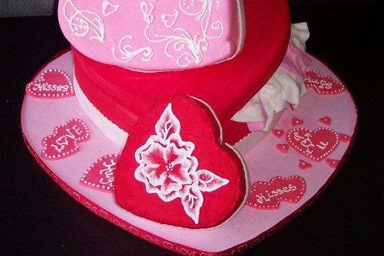 This is a whimsical heart shaped cake. The cake is covered in fondant with fondant tissue paper. The small heart is designed with a delicate brush embroidered flower. All work is done in sugar and is completely edible.