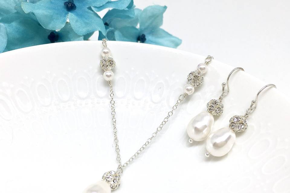 The pendant was created with a 10mm teardrop Swarovski pearl topped with a 6mm crystal ball bead. Solid sterling silver chain and earwires. https://twobewedjewelry.com/product/teardrop-pearl-bridal-necklace-set-swarovski-pearl-crystal-ball-accent-rachel-collection-bjs-rach/