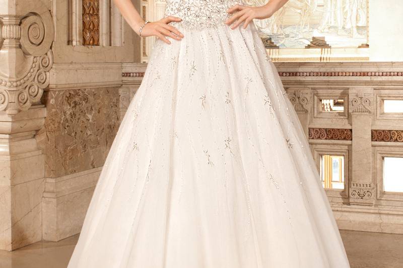 C223This sophisticated, form fitting, luxe satin wedding gown features exquisite embellished embroidery on the bodice and sheer long sleeves. The dramatic illusion back features accents of beaded embroidery and a button closure.