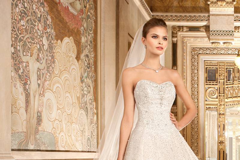 574This timeless, sparkling ball gown features a jewel encrusted bodice and sprays of beading throughout the tulle skirt. The lace-up back features a chapel train.