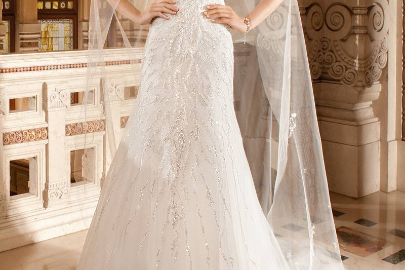 587This modified a-line gown features magnificent beaded vine embroidery over tulle that cascades from the bodice into the skirt. The low back features a chapel train.