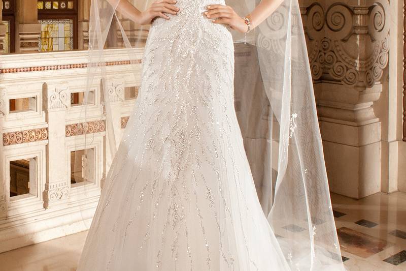 575This sleeveless, beaded tulle, modified a-line gown with Sweetheart neckline features a high illusion neck accented with jeweled embroidery. The dramatic sheer illusion back features a button closure and chapel train.