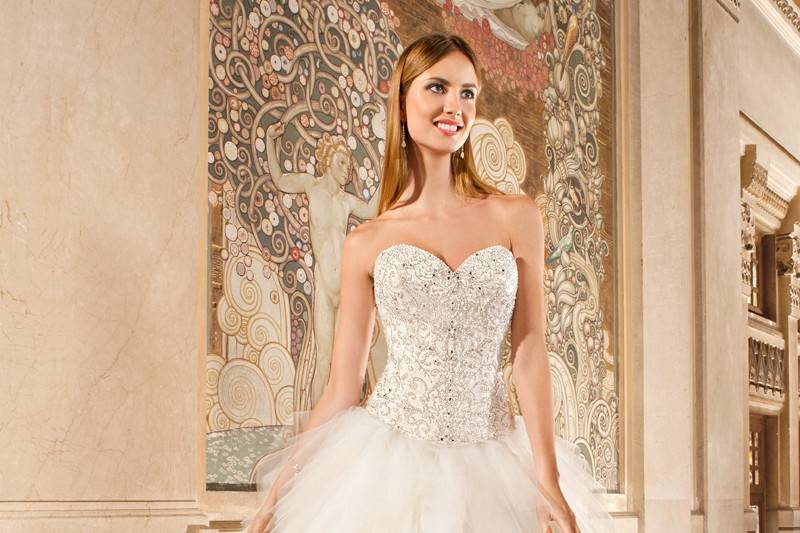 579This unique ball gown features a magnificent bodice adorned with elaborate beaded embroidery with jeweling and a full multi-tiered tulle skirt. The back features a corset lace-up and chapel train.