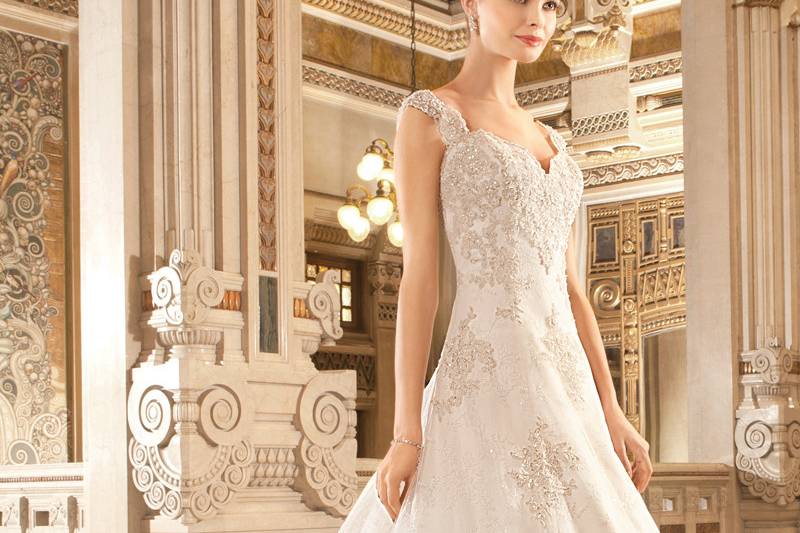 1482This flowing fit n flare gown with a v-neckline features sculpted straps that flow into a plunging open back. The bodice is adorned with delicate lace and accents of crystal beading that cascade into the tulle skirt and sweep train.