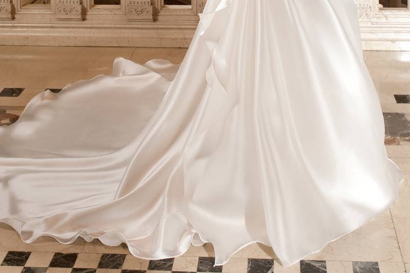 3222This satin organza, sleeveless, fit n flare gown features a pleated sweetheart silhouette with a sheer jeweled neckline and low v-back. The back is finished with a chapel train.