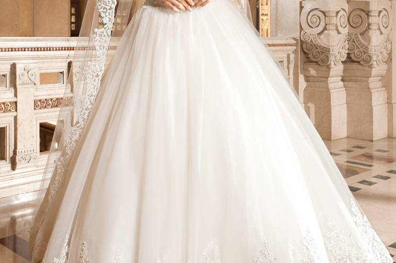 4328This beaded tulle fitted a-line gown features a sweetheart silhoutte with a sheer beaded overlay on the neckline and long sheer, beaded sleeves. The low back features a button closure and semi-chapel train.