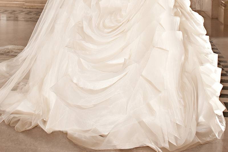 270This romantic tulle gown features a sweetheart neckline dropped waist and lace-up closure. The bodice and sheer cap sleeves are embellished with embroidered lace. The multi-tiered full ruffled skirt flows into a chapel length train.