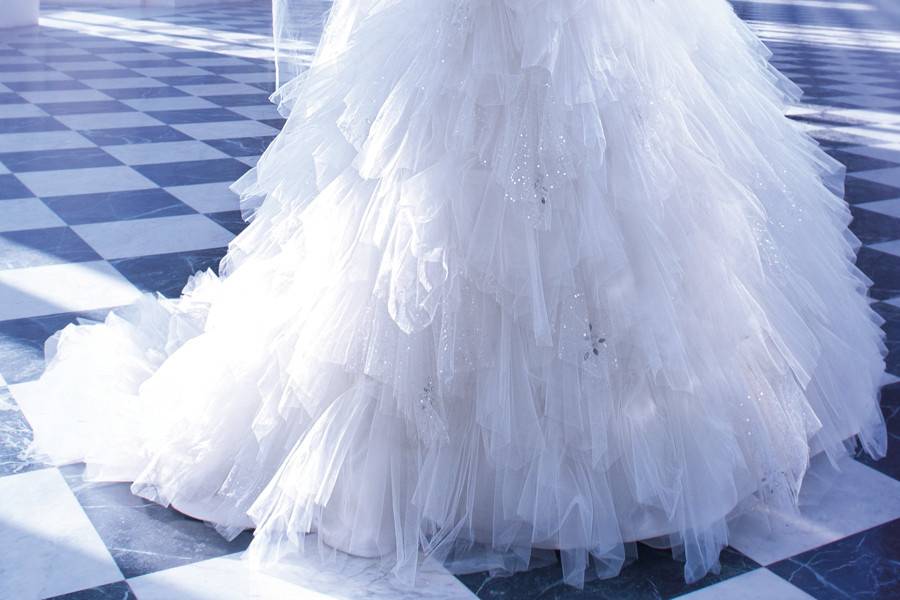 548Strapless Tulle bridal gown with a Sweetheart neckline elaborate jeweled embroidery on bodice and lace-up back. This wedding gown features a Basque waist and multi layered handkerchief full skirt with sprays of beading and attached Chapel train.