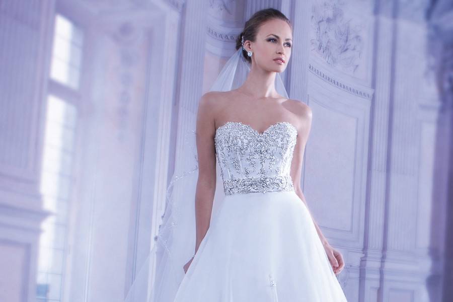 548Strapless Tulle bridal gown with a Sweetheart neckline elaborate jeweled embroidery on bodice and lace-up back. This wedding gown features a Basque waist and multi layered handkerchief full skirt with sprays of beading and attached Chapel train.