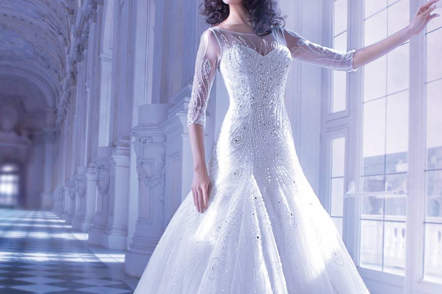 555Sparkling Tulle ball gown wedding dress with a sweetheart bodice, sleeveless, sheer jeweled neckline and V-back with zipper. This wedding gown also features a belt with jeweled buckle motif and attached Chapel train.