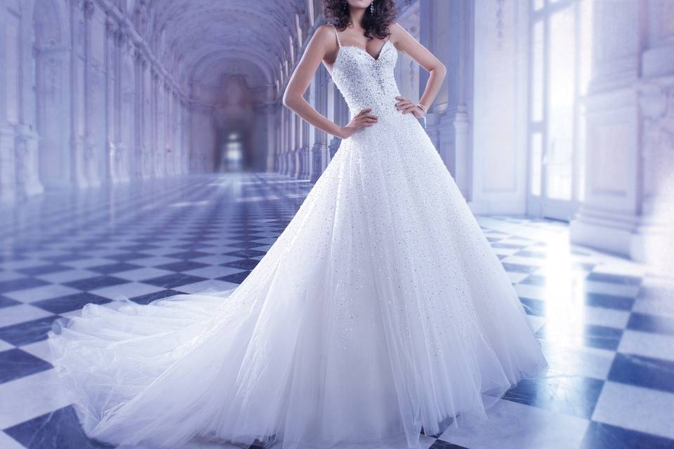 560Beaded tulle ball gown wedding dress with a dramatic V-neckline, spaghetti straps and plunging back. The sparkling tulle skirt on this bridal gown features a Chapel train.