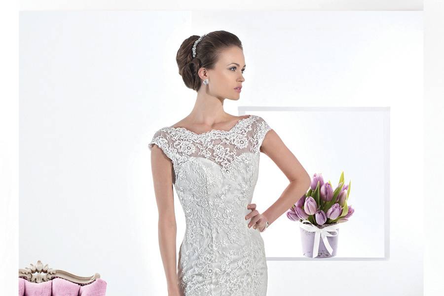 1457Chantilly lace sheath wedding gown with a sheer lace neckline and low V-back. This bridal dress features a removable satin belt and Chapel length train.