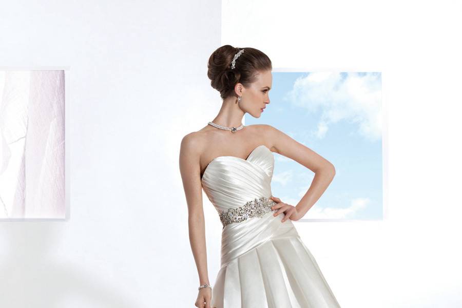 3202Satin Organza, A-line wedding gown with flowers on one-shoulder and asymmetrical pleating on bodice. The skirt on this bridal dress features a side split with ruffles and attached Chapel train.