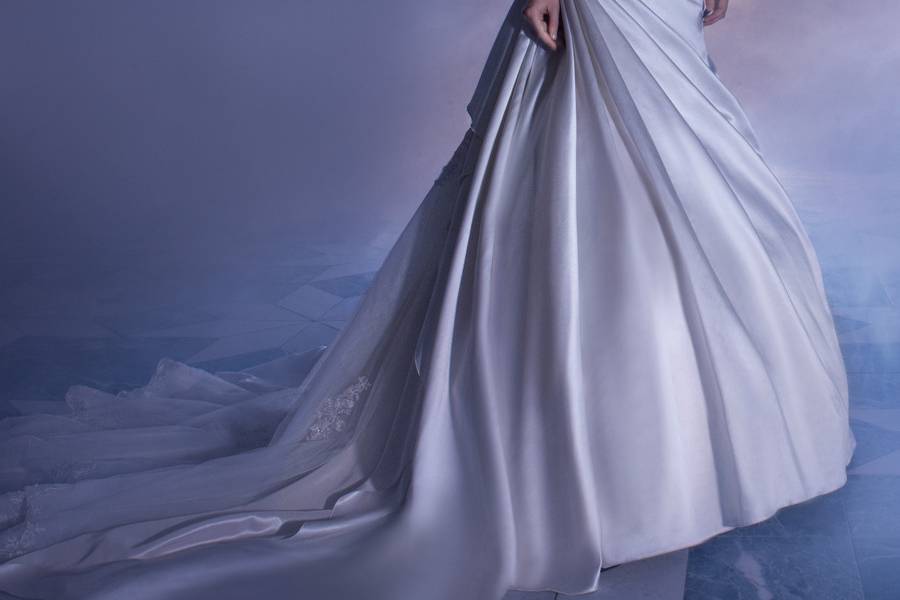 4320Satin, A-line wedding dress with a V-neckline, ¾ length sleeves and asymmetrical pleated wrap waist and skirt. Upper bodice and sheer sleeves are embellished with beaded Venice lace. This bridal gown features a plunging back with lace-up and beaded lace over tulle underlay on Chapel train.