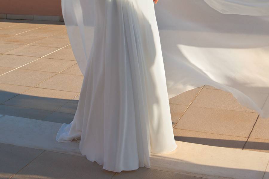 187Chiffon destination wedding gown with a Sweetheart neckline and sleeveless sheer beaded overlay with a low V-back and buttons. The flowing A-line skirt on this bridal dress features a Chapel train.