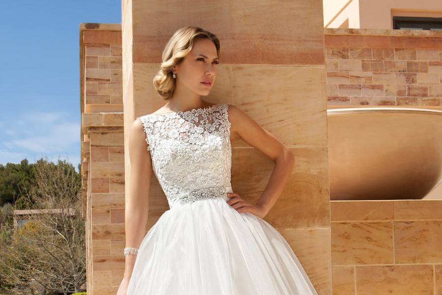 193Sleeveless Cocktail length destination wedding dress featuring a Venice lace bodice with a sheer neckline and full tulle skirt. This bridal dress also has a belt with jeweled appliqué.