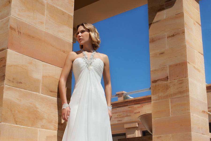 196Chiffon, A-line destination wedding gown with a ruched Empire bodice with beading and jeweled halter Strap. The skirt on this bridal dress features a Sweep train.