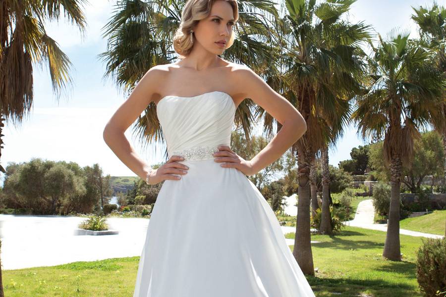 197Chiffon, A-line destination wedding gown featuring a ruched bodice with beading and a high, sheer beaded halter neckline. The low back on this bridal dress features sheer beaded halter straps, buttons and a Chapel length train.