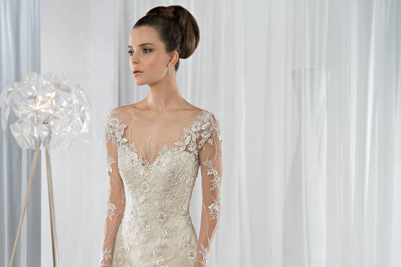 Style 581 <br> This striking beaded tulle, Fit-N-Flare gown features a sheer neckline and long sheer sleeves embellished with delicate beaded embroidery.     The low keyhole back is finished with buttons and a Chapel length train.