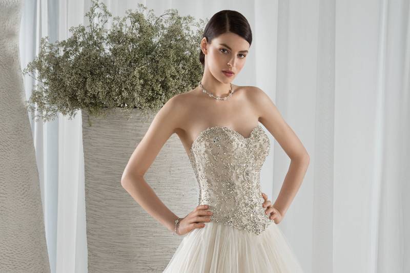 Style 584 <br> This striking strapless, Tulle Ball Gown with a Sweetheart neckline features a shimmering bodice with crystal beading and Basque waist.  The back features a lace-up closure and Chapel train.