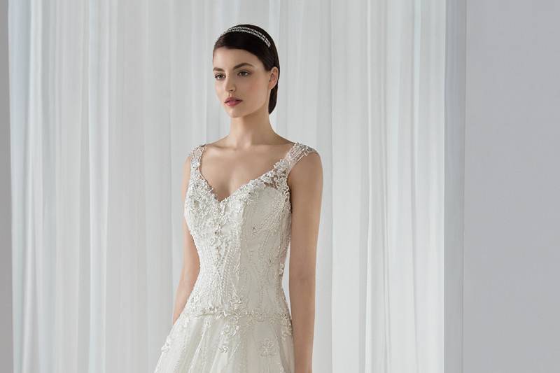 Style 592 <br> This Classic beaded lace over tulle A –line gown with V-neckline features delicate lace straps that transition into a sheer lace scoop back.  The back features buttons and a Chapel train.