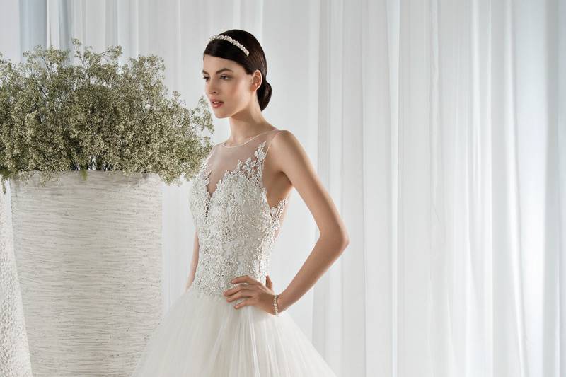 Style 602 <br> This dreamy sleeveless, tulle Ball Gown features a Sweetheart neckline and unique flower embroidery throughout the bodice, skirt and sheer illusion overlay transitioning into a low illusion back with buttons.