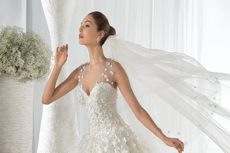 Style 602 <br> This dreamy sleeveless, tulle Ball Gown features a Sweetheart neckline and unique flower embroidery throughout the bodice, skirt and sheer illusion overlay transitioning into a low illusion back with buttons.