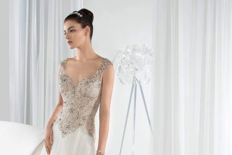Style 618 <br> This timeless Tulle A-line gown with an intricately beaded bodice and Basque waist, transitions into a keyhole back with button closures and a Chapel length train.