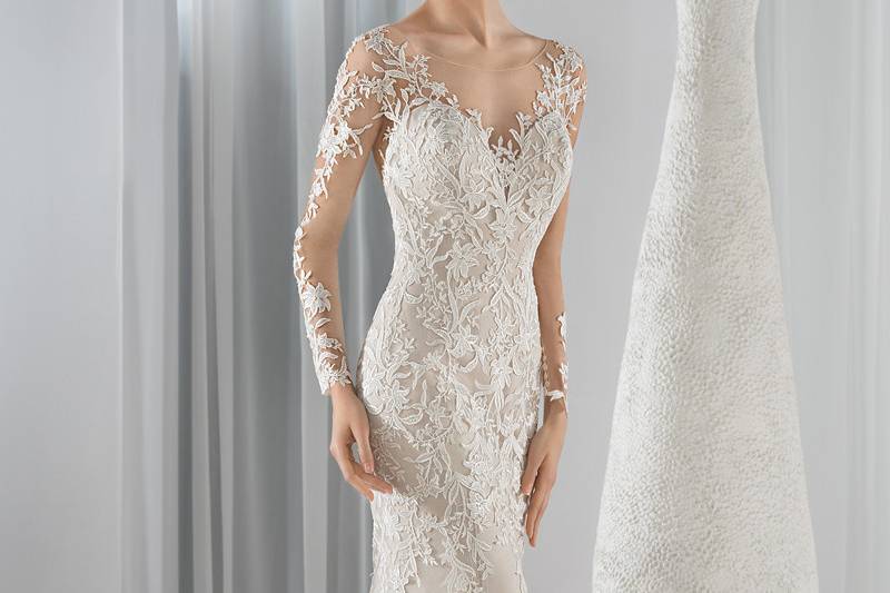 Style 631 <br> This timeless lace Fit-N-Flare gown features an illusion  neckline and long sheer sleeves.  The dramatic low illusion back is finished with button closure and a Chapel train.