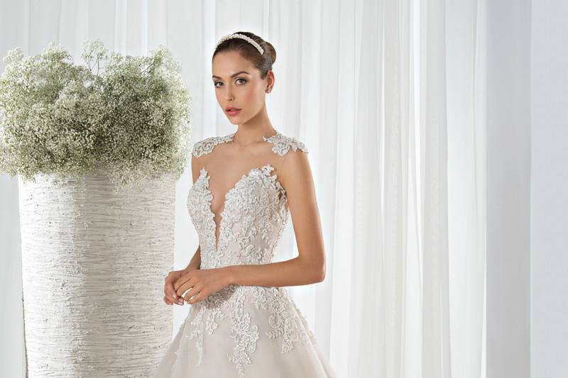 Style 632 <br> This Classic Tulle Ball Gown is embellished with a lace bodice with a high illusion neckline and plunging sweetheart. The lace cap sleeves transition to a sheer illusion back and a Chapel length train.