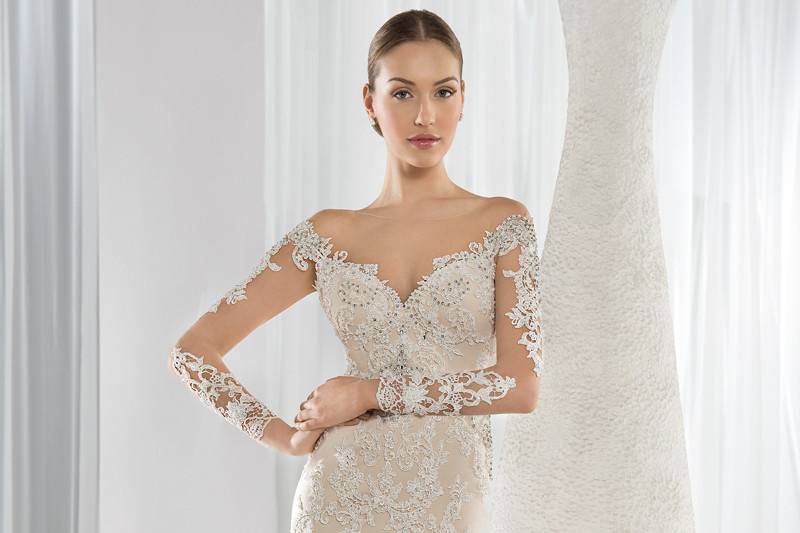 Style 635 <br> This Chic lace Sheath gown features a high sheer neckline and long sleeves with appliques of lace. The low sheer back is embellished with button closure and a Chapel train.