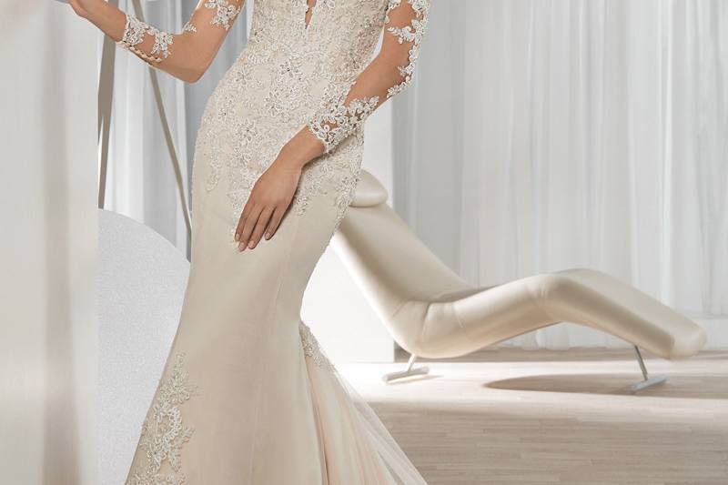 Style 639 <br> This shimmering beaded lace Fit-N-Flare gown features a bateau illusion neckline with sheer long sleeves and lace appliques, that transition to the sheer dramatic back. The back is embellished with button closure and a Chapel train.