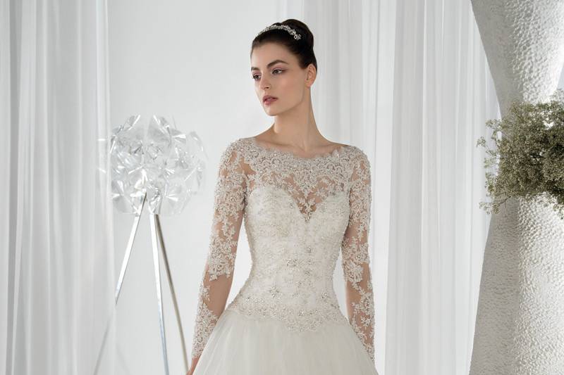 Style 641 <br> This romantic Ball Gown features an off the shoulder beaded lace neckline with long lace sleeves. The low scoop back is embellished with button closures and a tiered tulle Chapel train.