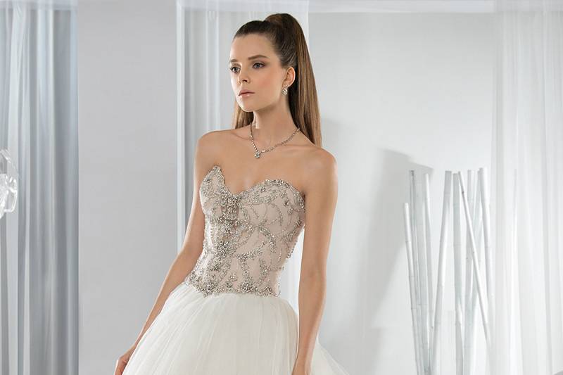 Style 653 <br> This classic Ball Gown is embellished with intricate beading on a sweetheart neckline bodice featuring a Basque waist. The back is embellished with a lace-up closure and Chapel train.