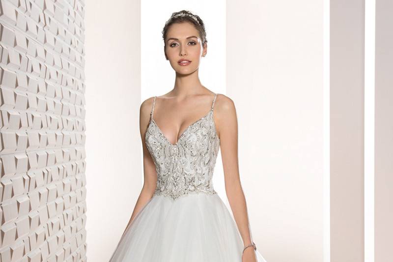 Style 724 <br>	This shimmering Ball gown with richly beaded bodice and Sweetheart neckline features Sheer illusion on the sleeves and upper neckline with sunbursts of crystals and beading.  The back features a dramatic low V-back and Chapel train.