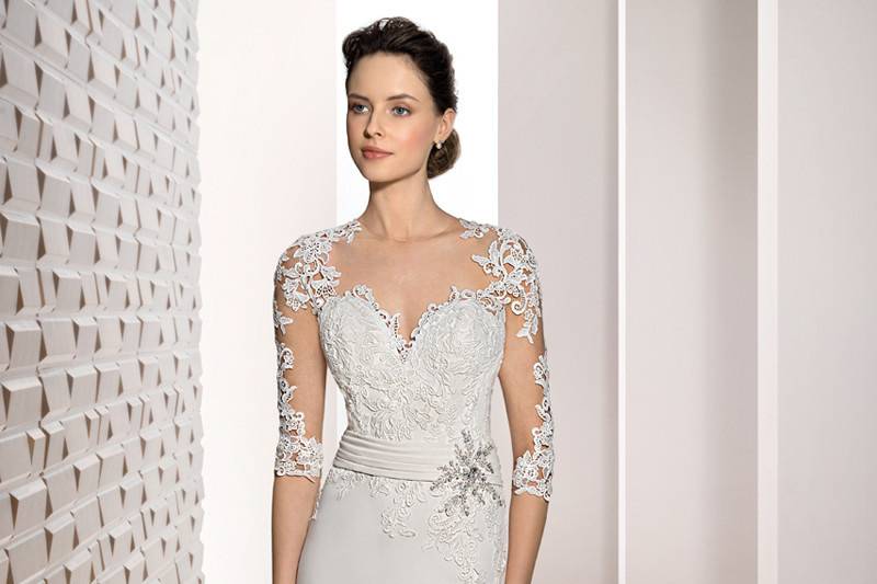 Style 701 <br>	Delicate lace over barely there illusion sleeves that flow into a dramatic illusion back with buttons turn this Crepe contemporary sheath with Sweetheart neckline and Sweep train into a classic stunner.