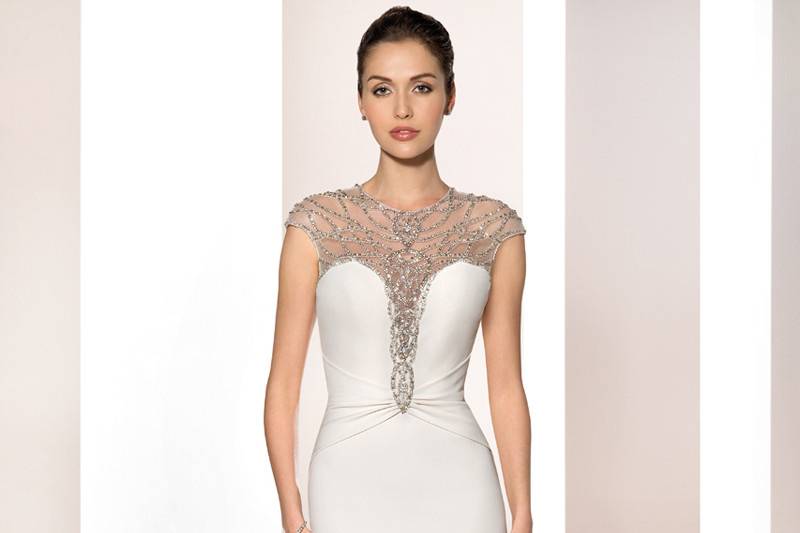 Style 699 <br>	Simple and sophisticated, this elegant strapless Crepe Sheath with Sweetheart neckline and bead encrusted applique on the side waist features understated embroidered lace and a Chapel train.