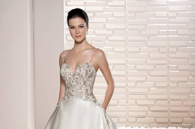 Style 691 <br>	Timeless elegance describes this sleeveless, Mikado A-line gown with crystal beaded belt and inverted box pleats that flow into a Chapel train.  The soft Sweetheart neckline features a sheer overlay with a jewel encrusted neckline.