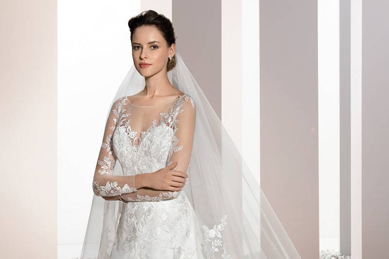 Style 688 <br>	Chantilly lace over tulle embellishes this magnificent A-line gown with delicate lace over sheer sleeves and Sweetheart neckline with illusion overlay that flows into a dramatic sheer back with buttons.  The back features a lace embellished Chapel train.